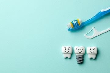 Healthy white teeth and implants are smiling on mint green background with toothbrush and dental...