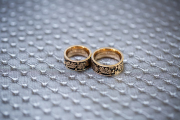 Obraz na płótnie Canvas gold wedding rings with a pattern lie on a gray fabric