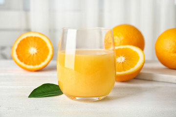 Glass with orange juice and fresh fruit on table