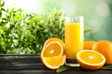 Glass with orange juice and fresh fruit on wooden table, space for text