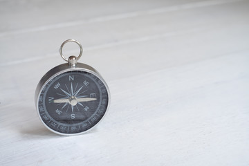 Compass on white wooden table background, journey planning concept