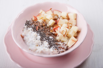 Homemade muesli with nuts and apples in a pink plate