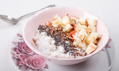 Homemade muesli with nuts and apples in a pink plate