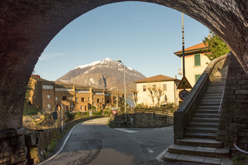 Italy, Bellagio, Lake Como, Snow capped alps under arch with staircase winding road