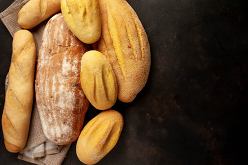 Various fresh bread and buns on a stone table. 