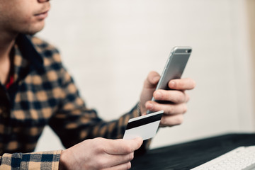 Cropped picture of man with credit card white pattern and phone