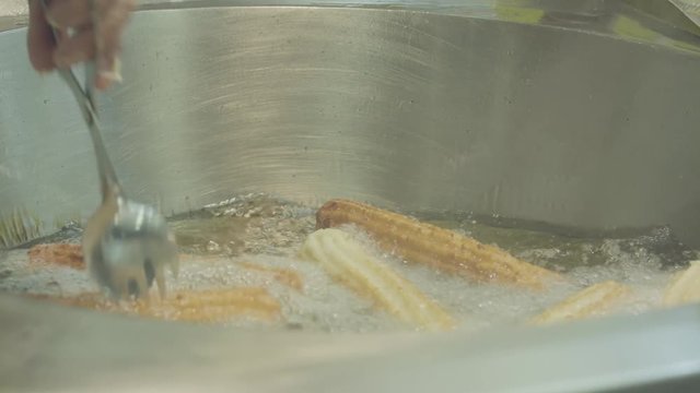 A woman frying farturas  (portuguese name of a cultural food)  in deep oil at a portuguese summer village festival