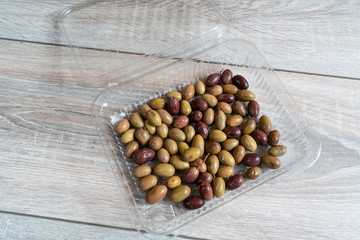 some olives in a plastic pan on the wooden table