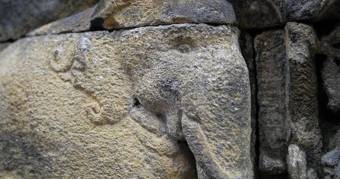 Borobudur ancient stone wall sculpture. Indonesia. Close up panning shot across features relief in stone carvings.