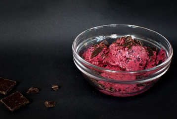 Homemade ice cream with berries in a bowl on black background.