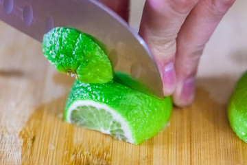 man cuts juicy lime slices on a wooden table, close up, blurry background