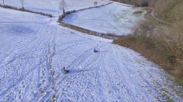 Arial view of two girls sledging in the snow in the Forest of Dean, Gloucestershire.
