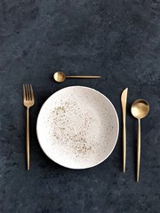 white plate with golden cutlery on dark background