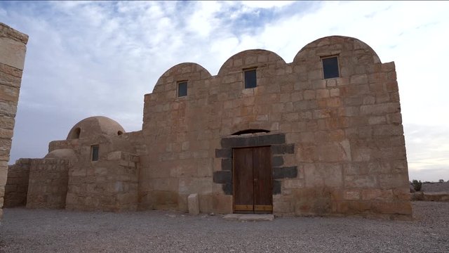 Wide Pan Shot of UNESCO World Heritage Site Qasr Amra Desert Castle with Three Domes on a Cloudy Day