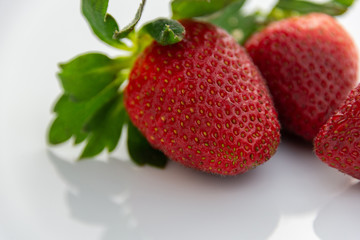 Group of red strawberries with green leaves isolated