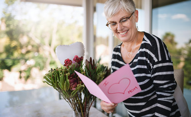 Happy mother's day. A mature woman, mother and grandmother reading a handmade mother's day card...