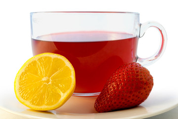 Glass cup of hot aromatic red tea with strawberry and lemon