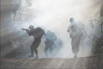 Army patrols in the forest, coming out of the smoke and fog. - obrazy, fototapety, plakaty