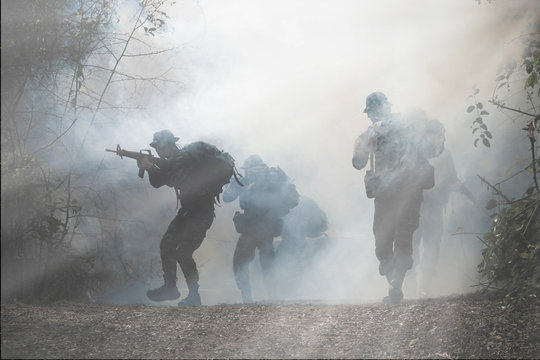 Army patrols in the forest, coming out of the smoke and fog.