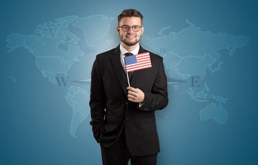 Cheerful businessman standing in front of a map with flag on his hand
