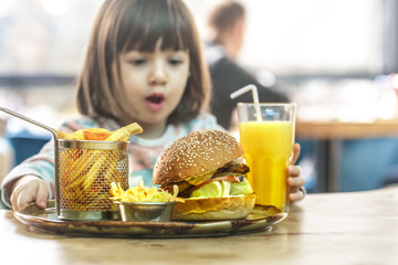 Little girl eats in a fast food cafe