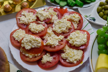 A dish of tomato with cheese and garlic on a white plate.