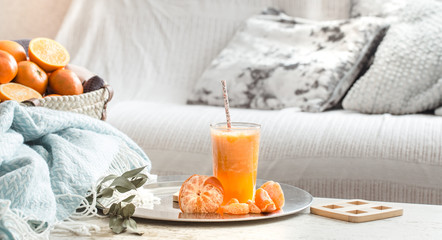 Freshly-grown organic fresh orange juice in the interior of the house, with a turquoise blanket and...