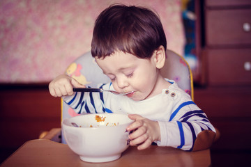 The boy eats himself from the plate. An independent child. The child eats