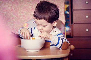 The boy eats himself from the plate. An independent child. The child eats