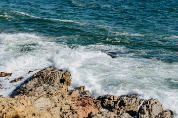 Mediterranean Sea water waves crashing on the shore rocks