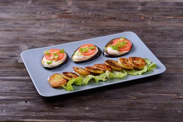fried eggplant and potatoes with tomato and salad on a plate