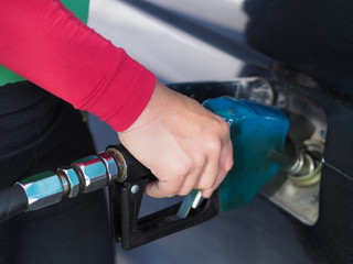 Close up hand of man pumping gasoline fuel in car at gas station.
