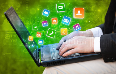 Hand using laptop with bouncing colorful application and global reports and graphs concept
