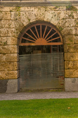 Fototapeta na wymiar Italy, Bellagio, Lake Como, a rustic gate in front of a brick building