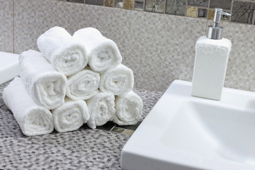 Stack of clean white towels on ceramic countertop in bathroom