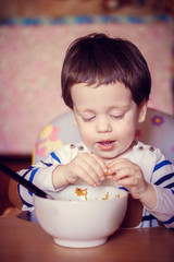 The boy eats himself from the plate. An independent child. The child eats