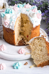 Tasty decorated Easter cakes lie on a round white wooden plate on a   white wooden table.    One Easter is cut and an appetizing morsel lies on a white wooden round board.