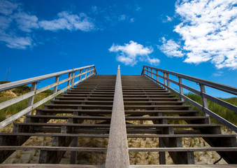 Obraz premium Treppe zum Strand ohne Menschen. Aufstieg mit Blick in den blauen Himmel