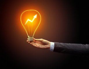 Hand holding light bulb on dark background. New Eco idea concept