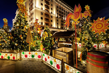 Festive decoration of the traditional holiday Shrovetide near the Kremlin walls on Manezhnaya Square in Moscow. Festive lights of the city of Moscow on the background of the night sky.