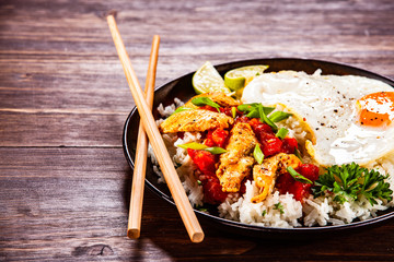Grilled meat, white rice,fried egg vegetables on wooden table