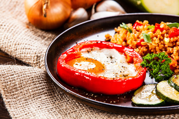 Fried egg, groats and vegetables on wooden table