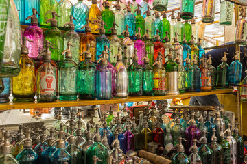 Rows of coloured glass antique soda bottles lined up at a flea market in San Telmo, Buenos Aires, Argentina
