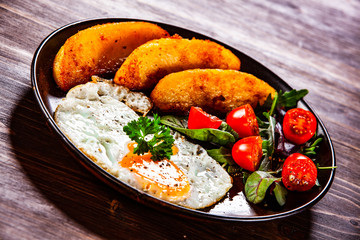 Fried egg, baked potatoes and vegetables