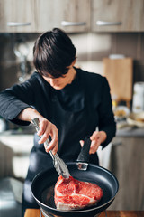 Chef frying ribeye steak in a pan