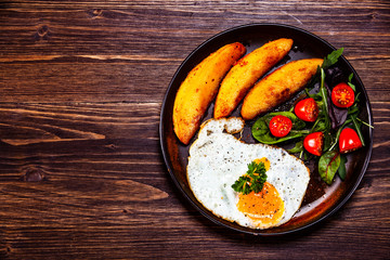 Fried egg, baked potatoes and vegetables