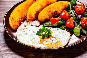Fried egg, baked potatoes and vegetables