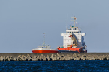 RED CARGO VESSEL -  Merchant ship is sailing along waterway to the port of Swinoujscie