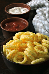 Corn rings in a bowl with white and red sauce. Quick snack. Flat Lay.