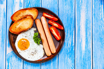 English breakfast - fried egg, sausages, toasts and vegetables